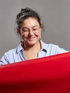 Magali Billy dans son atelier regardant un cuir rouge. 