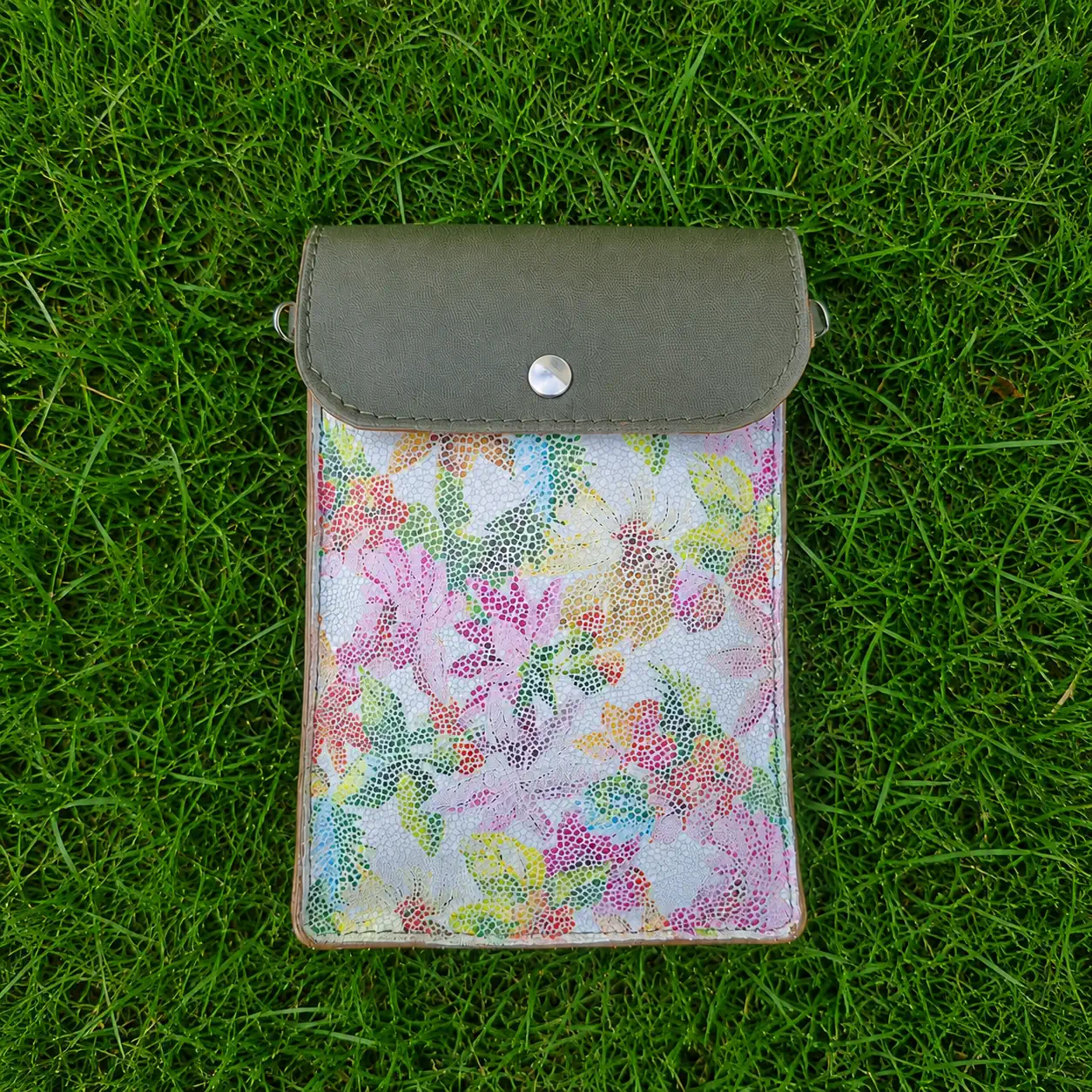 Pochette artisanale en cuir vert kaki et blanc à motifs fleuris colorés, portée en bandoulière.