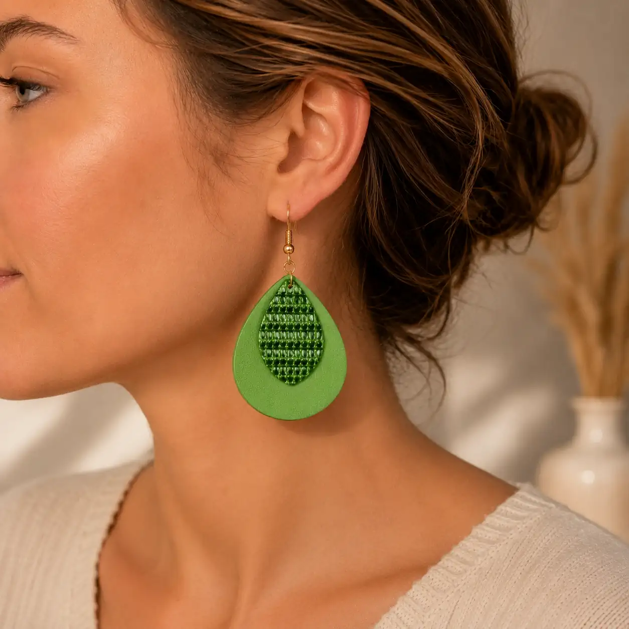 Boucles d'oreilles en cuir vert clair et vert brillant portées.