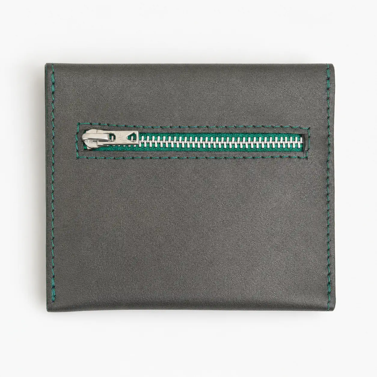 Dos d'un porte-monnaie artisanal en cuir gris foncé et piqûre verte, avec poche zippée extérieure