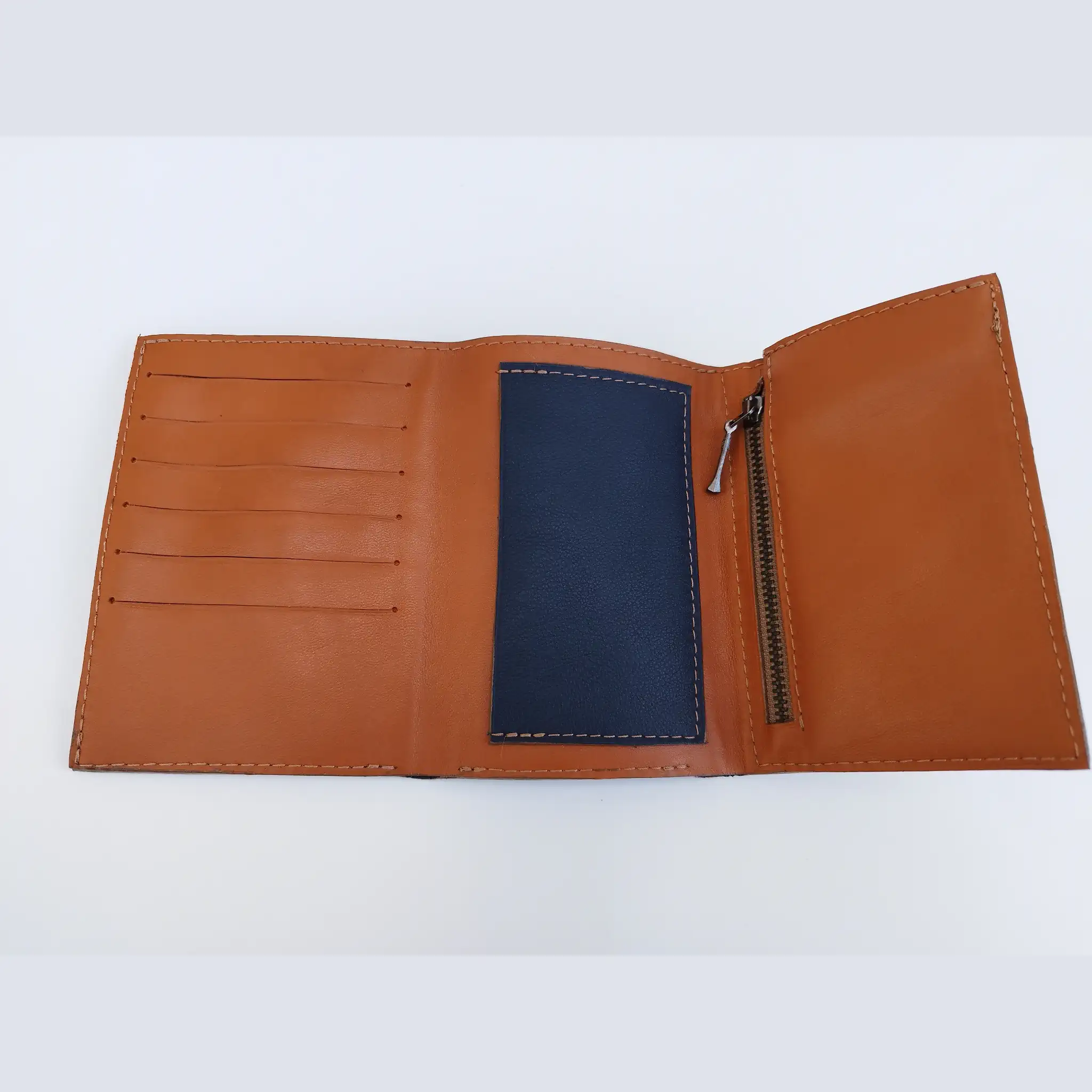 Grand portefeuille homme en cuir camel et bleu marine ouvert, avec rangements pour cartes, billets et poche zippée.