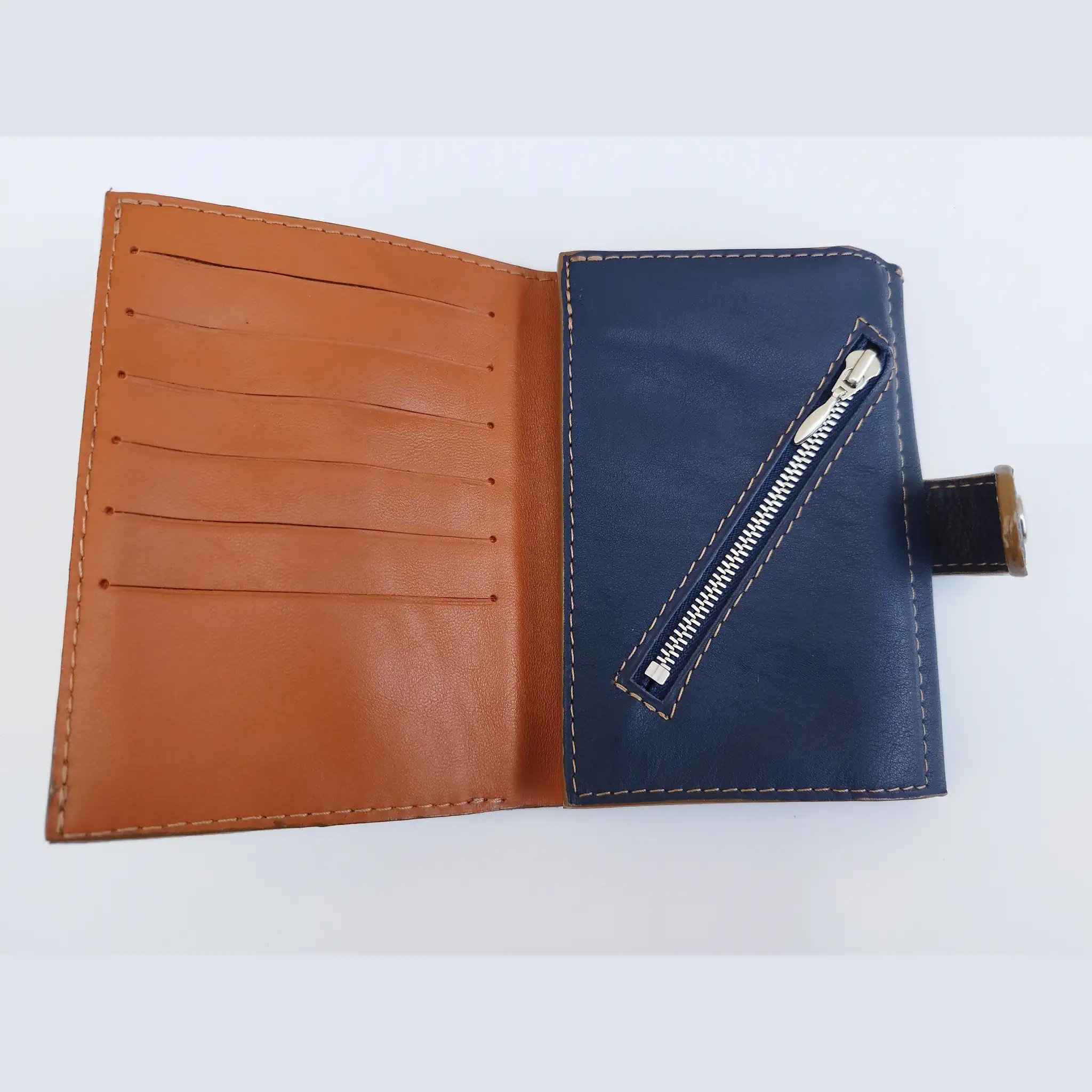 Portefeuille homme en cuir camel et bleu marine ouvert, avec six emplacements pour cartes et poche zippée.