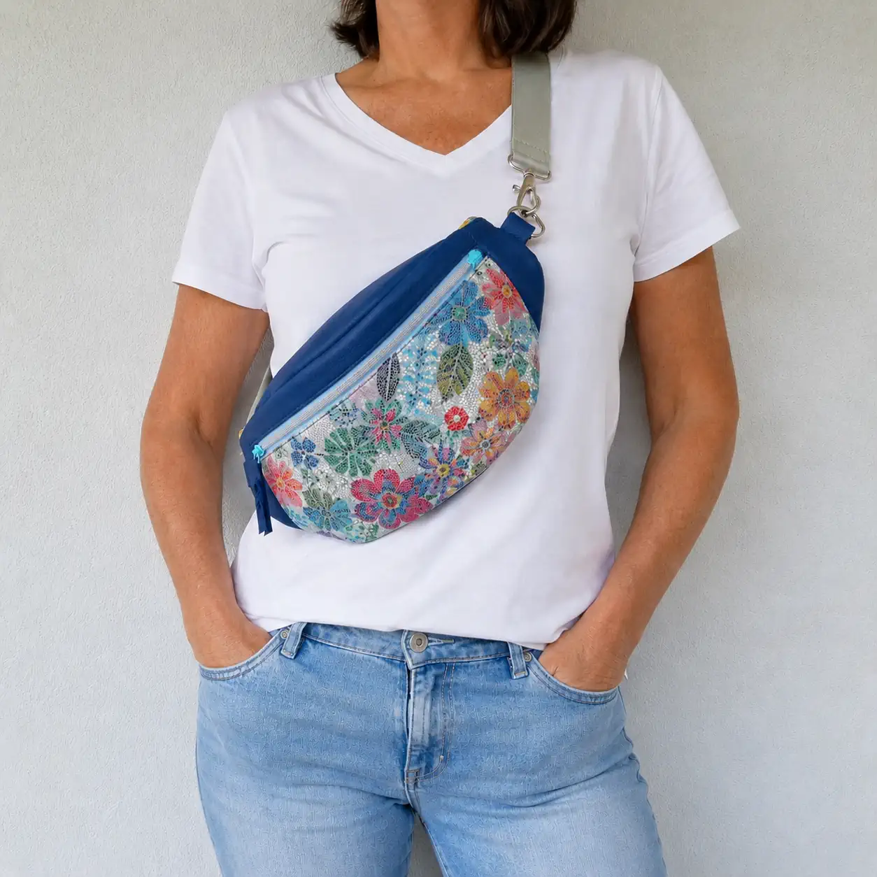 Sac banane artisanal en cuir bleu et cuir fleuri porté en bandoulière