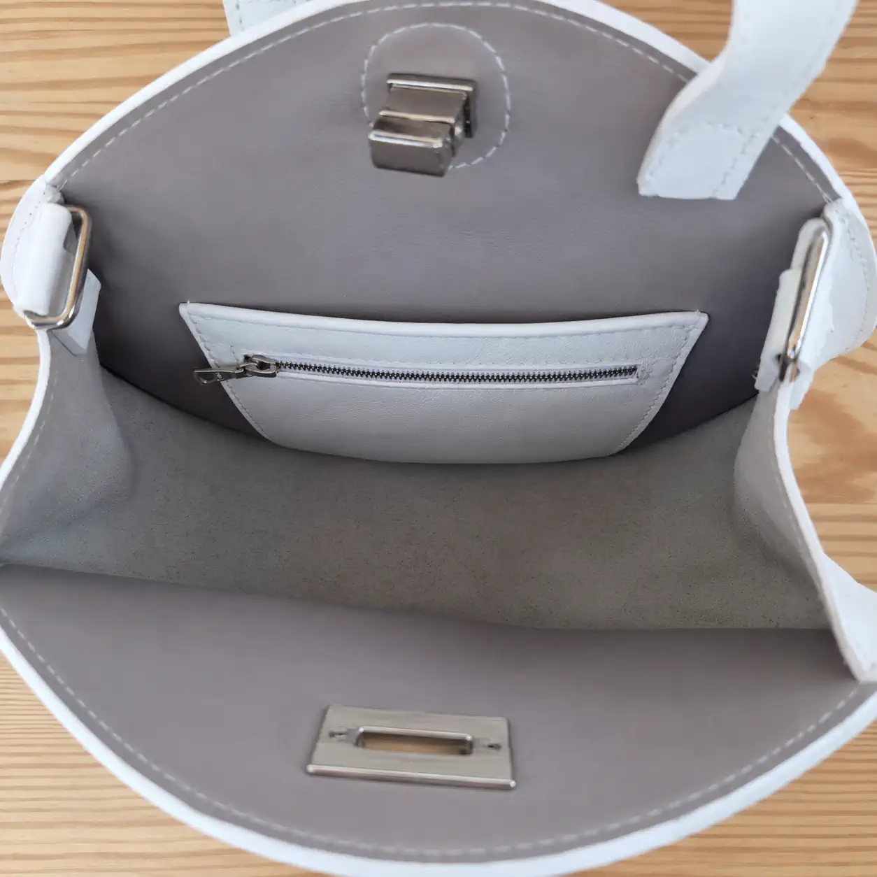 Intérieur du sac rond en cuir avec poche zippée.